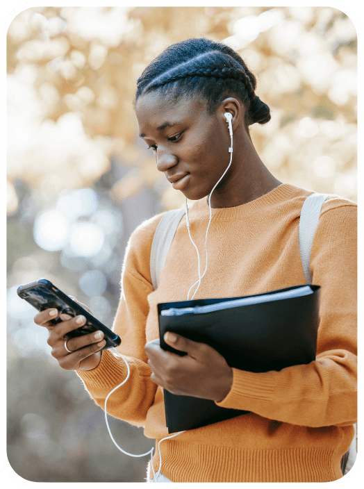 A woman with headphones on looking at her cell phone.